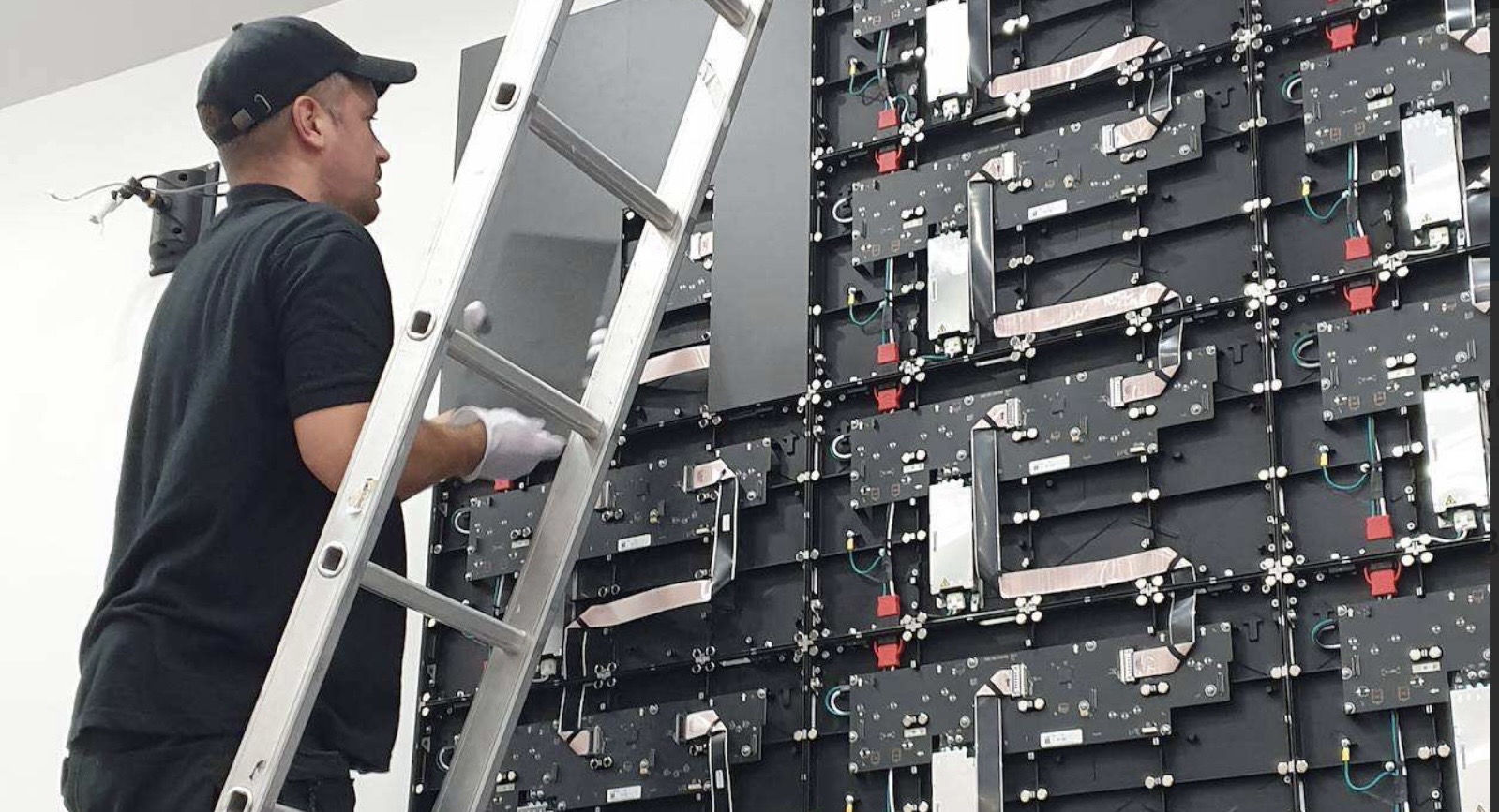 An engineer on a ladder installing the LED video wall at the SFRS Cambuslang auditorium